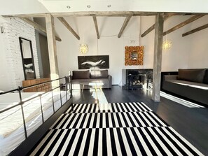 A modern interior with a black and white striped rug, a sofa, a fireplace, and a large abstract painting. - Uzupio2 Old Town Studio (Vilnius)