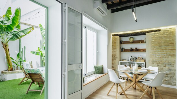 Een modern interieur met een eethoek, een schuifdeur naar een tuin en een bakstenen muur.