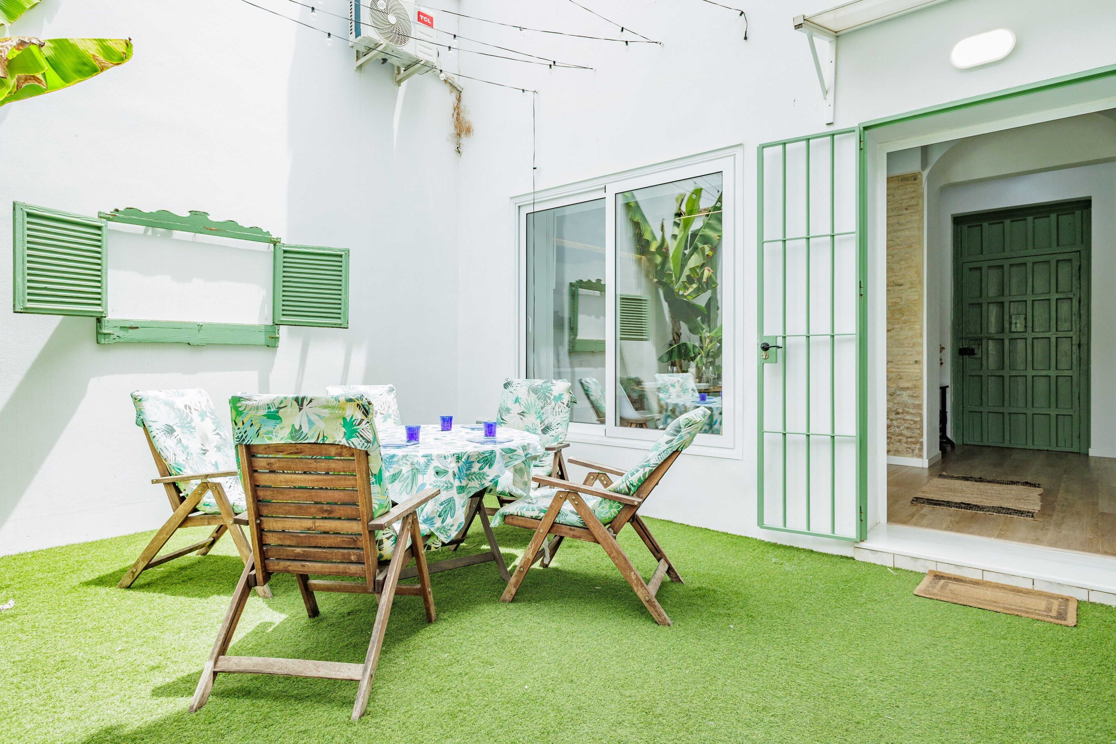 Une terrasse avec une table et des chaises, une fenêtre et une porte.