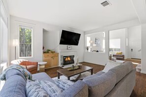 A living room with a fireplace, a flat-screen TV, a sofa, and a dining area.