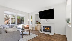 A modern living room with a fireplace, a flat-screen TV, and a sofa.
