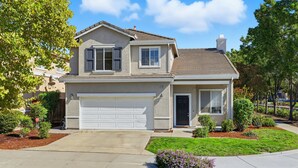 A two-story house with a garage, a front porch, and a well-maintained lawn.