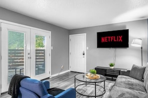 En moderne stue med et fladskærms-tv, en sofa, et sofabord og et tv-møbel.