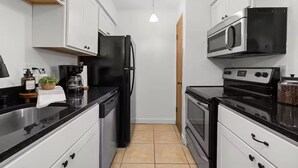 Eine kleine Küche mit Kühlschrank, Mikrowelle, Herd und Kaffeemaschine.