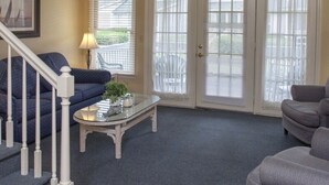 Una sala de estar con escalera, un sofá, una mesa de centro y una puerta con vistas.
