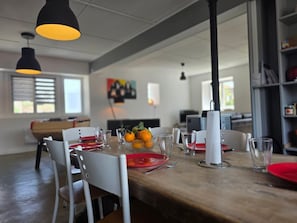 Un coin repas avec une table en bois, des chaises et un panier de fruits.