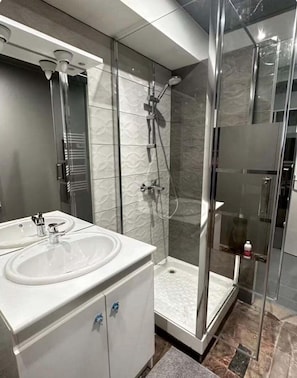 Une salle de bain moderne avec une douche à parois de verre, un meuble-lavabo à deux vasques et un miroir.