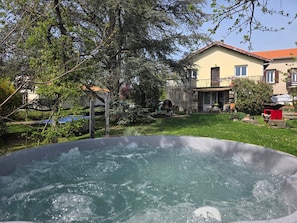 Un bain à remous dans un jardin, avec une maison en arrière-plan.
