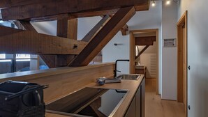 Una cocina moderna con vigas de madera, un lavamanos de acero inoxidable y un horno empotrado.
