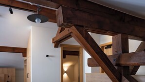 Una mesa de comedor de madera con sillas, una lámpara de techo y vigas de madera a la vista.