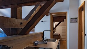 Una cocina moderna con encimera de madera, electrodomésticos integrados y una escalera que sube a un nivel superior.