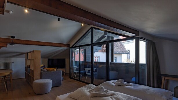 Una habitación con techo estilo loft, una cama, un escritorio y vistas amplias por grandes ventanales.
