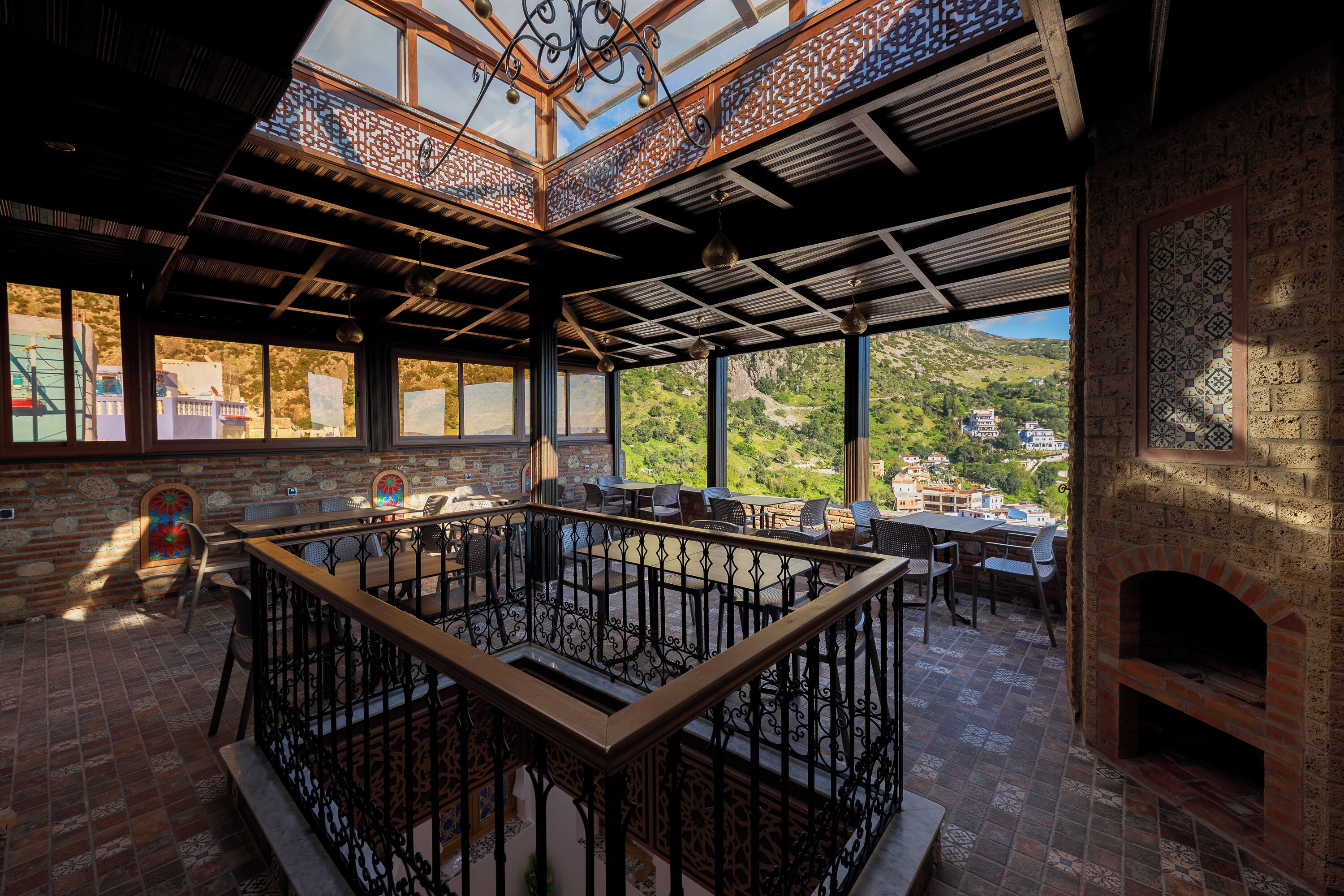 An interior with a central seating area, large windows, and a view of a mountainous landscape.
