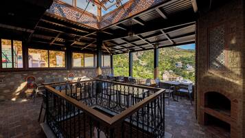 An interior with a central seating area, large windows, and a view of a mountainous landscape.