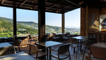 Un espacio de comedor al aire libre con mesas y sillas, ventanas amplias y vistas al campo.