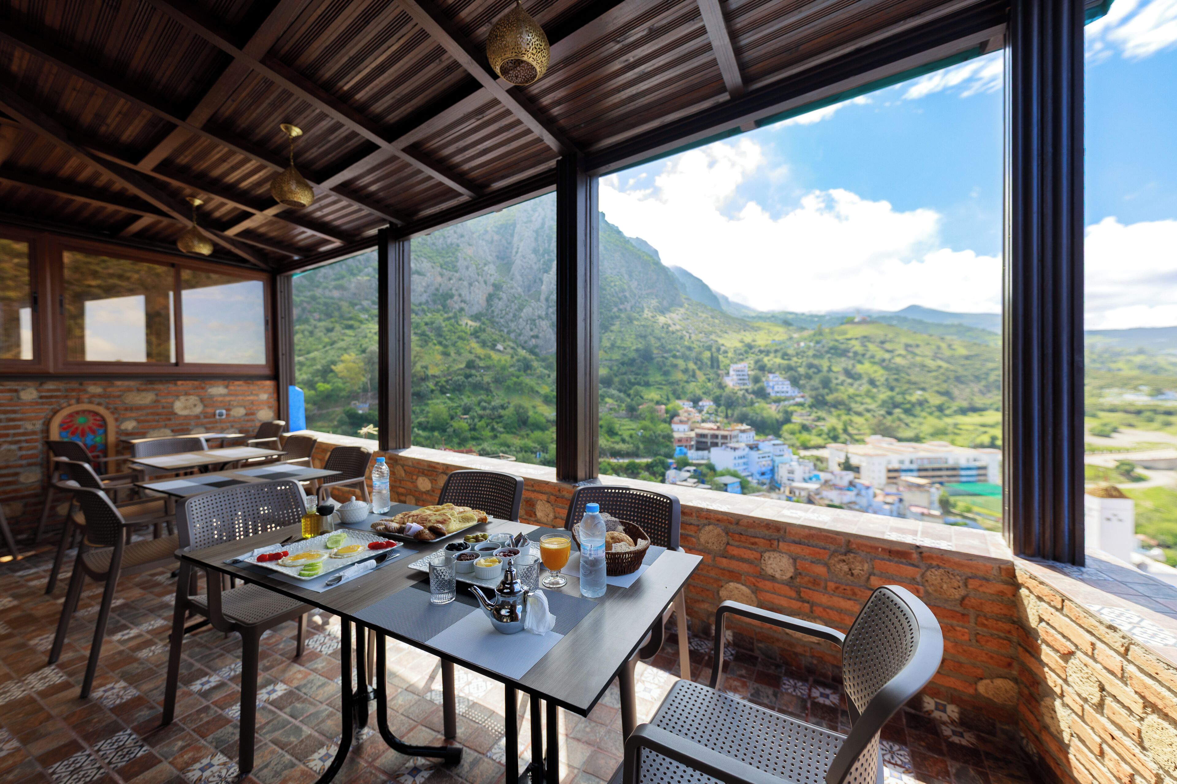 A dining area with a table set for two, overlooking a mountainous landscape.