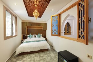 A bedroom with a bed, a TV, a decorative ceiling, and a window.