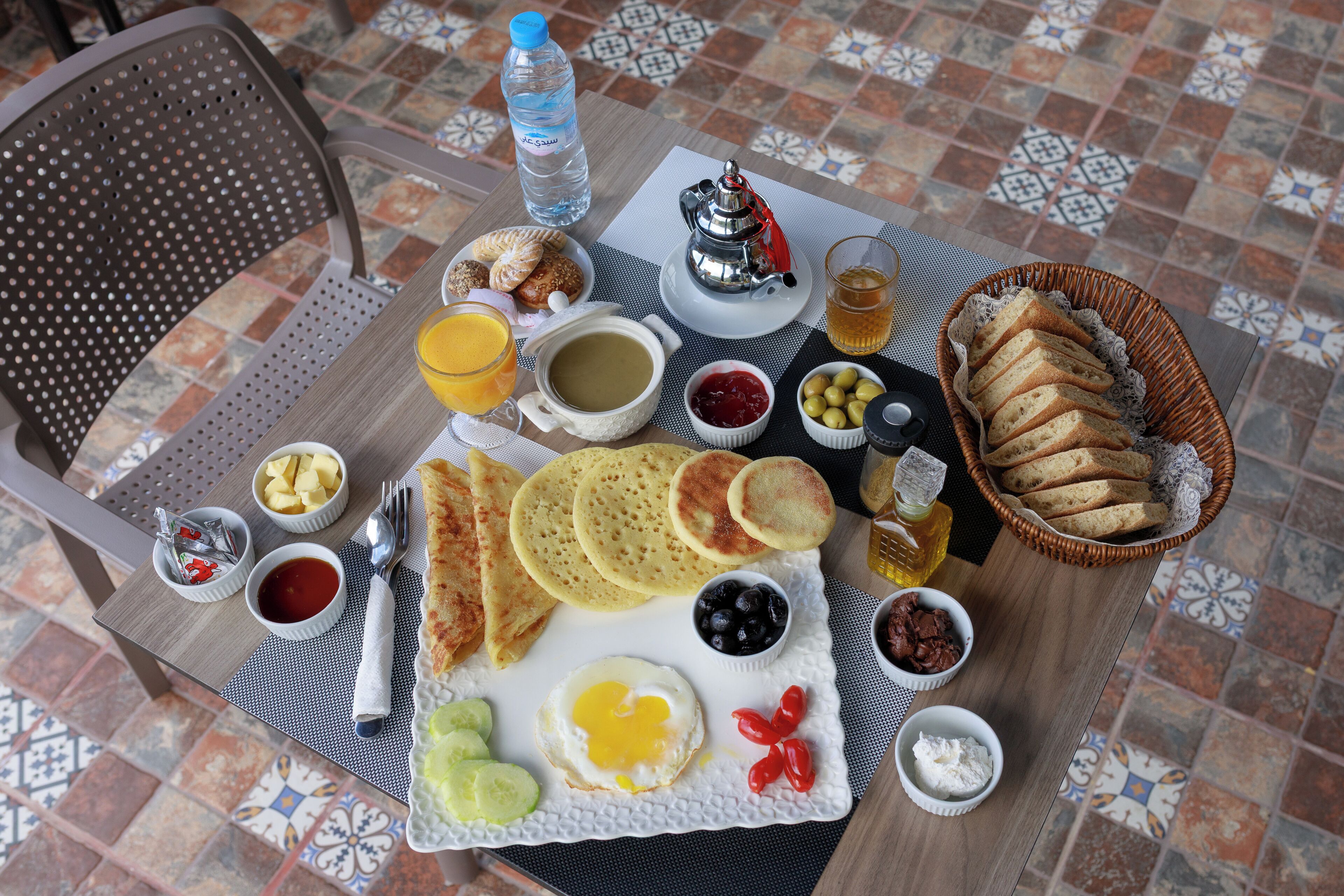 Une table de petit-déjeuner avec divers aliments, une bouteille d’eau et une tasse de thé.