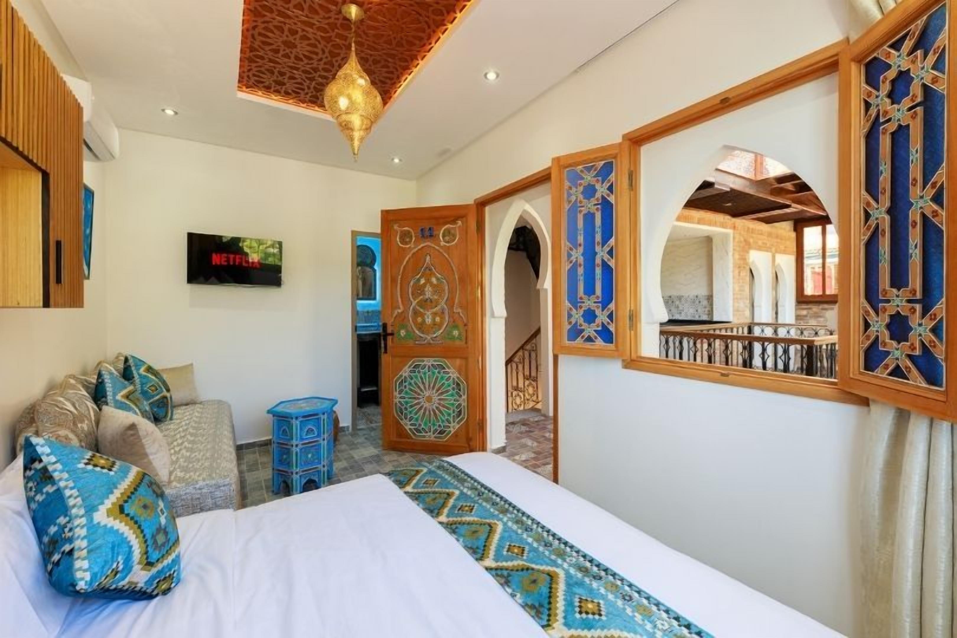 Habitación de hotel con cama, televisor, sofá y decoración en la pared.