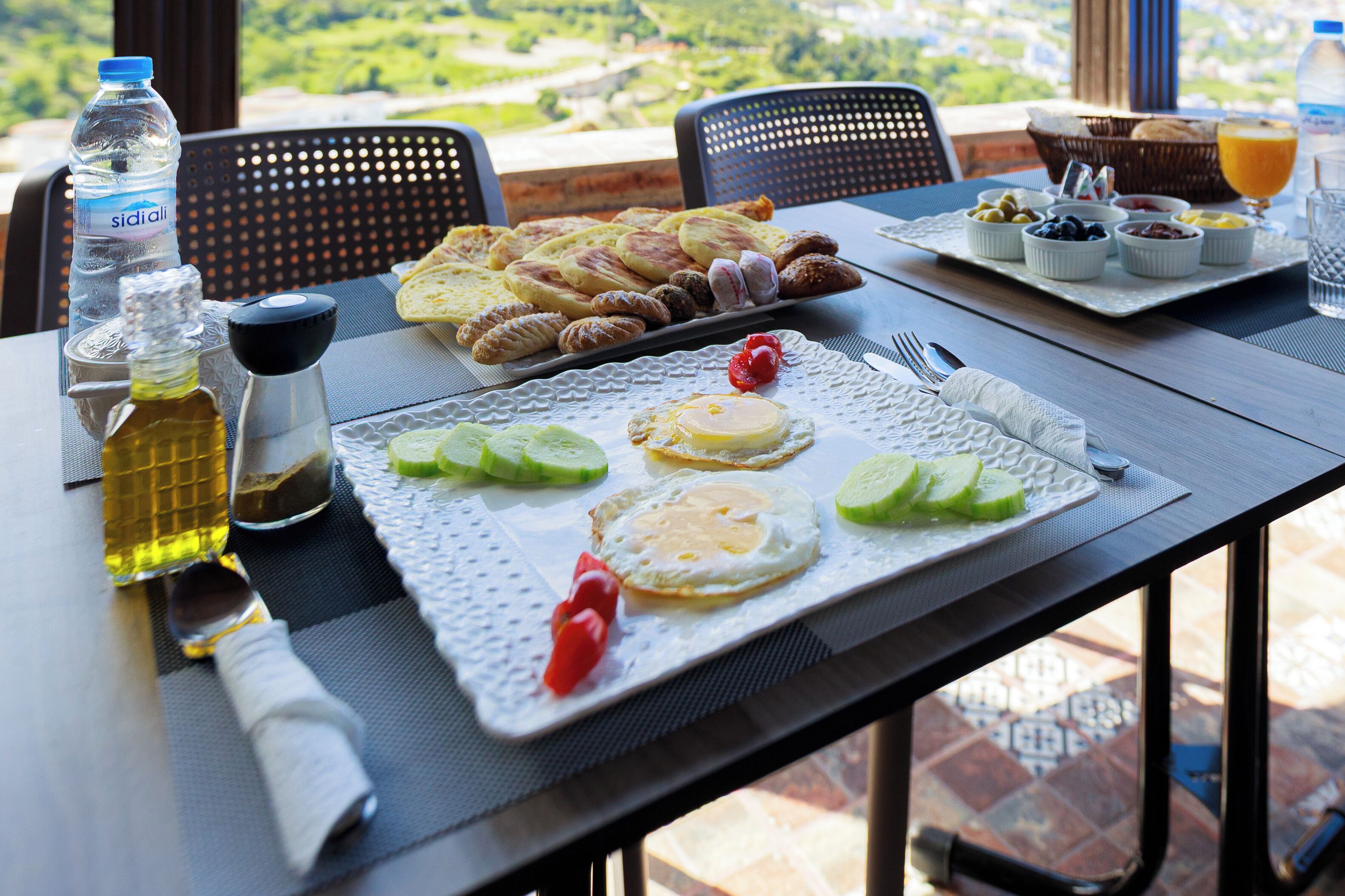 Une table de petit-déjeuner avec une variété d’aliments, notamment des œufs, du pain et une bouteille d’eau.