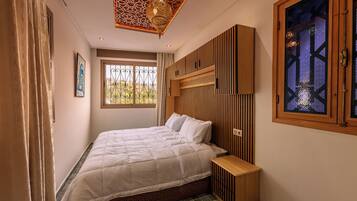 Un dormitorio con cama, mesita de noche, techo decorativo, ventana con vistas y un armario de pared.