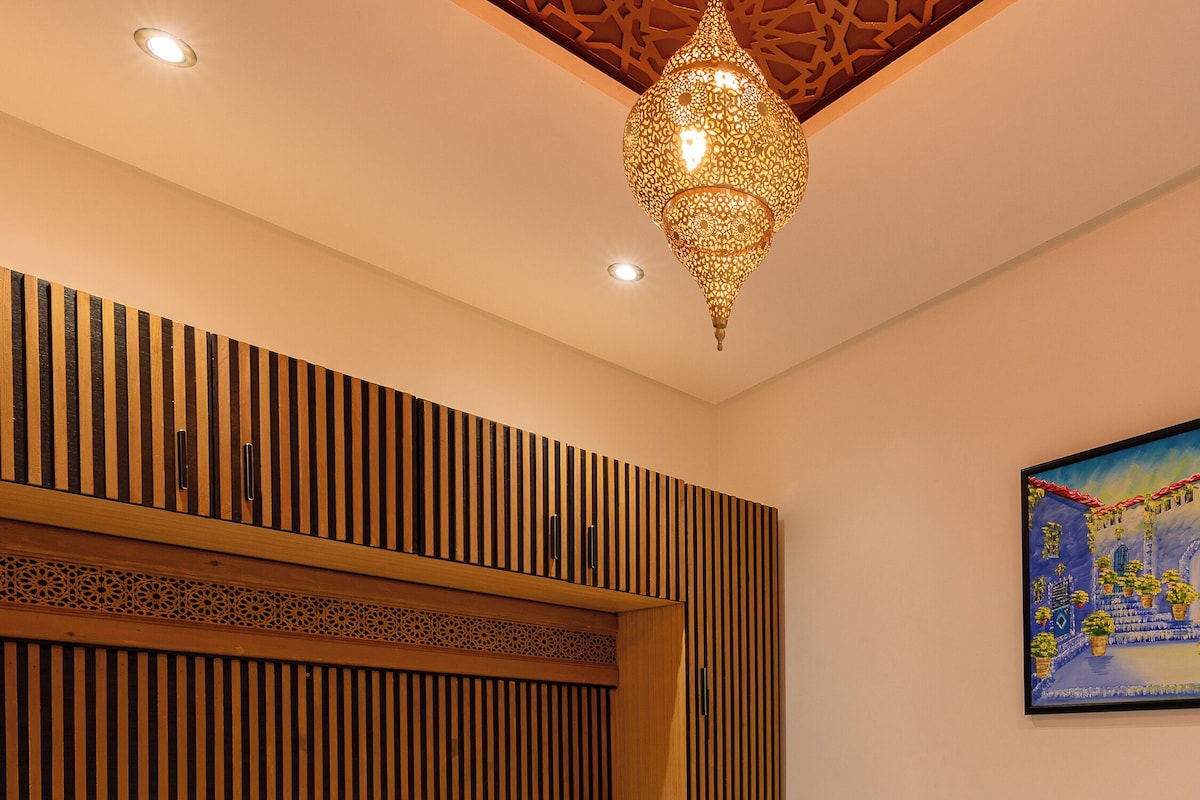 Une chambre à coucher avec un lit, des lambris en bois, un luminaire suspendu et un tableau au mur.