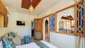 A room with a bed, a television, a decorative door, and a view of a balcony.