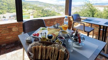 A table set with a variety of food items, including bread, olives, and a beverage, with a scenic view in the background.