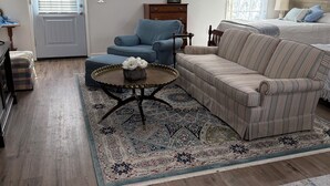 Sala de estar com sofá, poltrona, mesa de centro e tapete estampado.