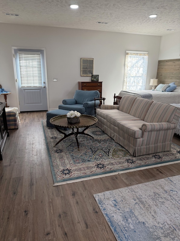 A living room with a sofa, armchair, coffee table, and a patterned rug.