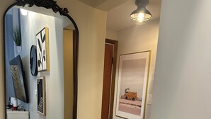 Un corridoio con uno specchio grande, opere d'arte incorniciate e una porta che dà su un'altra stanza.