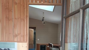 A compact kitchen with wooden cabinets, a dining area with a table and chairs, and a blue sofa in a small living space. - Studio cocoon wood & design - near GR + Le Palais + Plage (Le Palais)