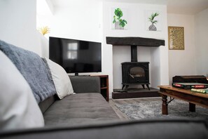 A living room with a sofa, a television, a fireplace, and a Scrabble game on a coffee table. - Ty Mari Crydd, Eglwyswrw (Eglwyswrw)