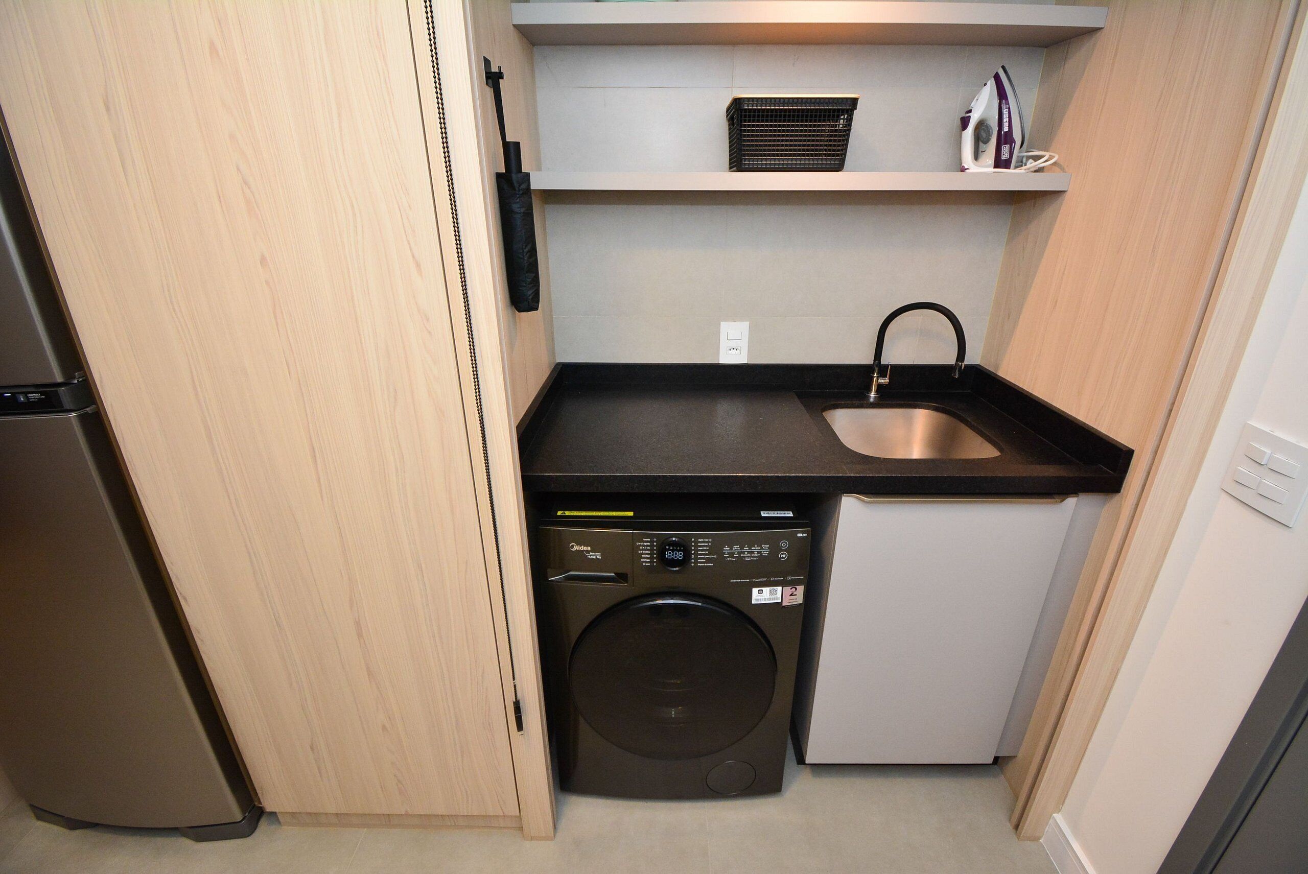 A compact kitchen with a washing machine, a sink, and a small countertop.