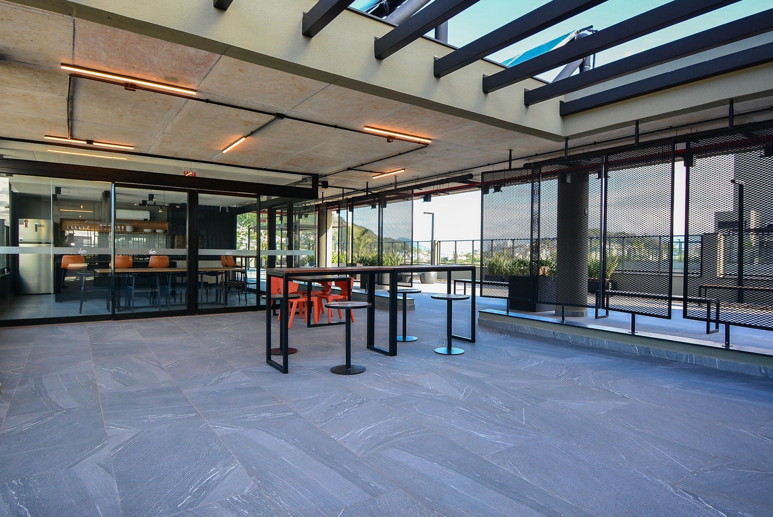 An indoor area with tables and chairs, large windows, and a view of the outdoors.
