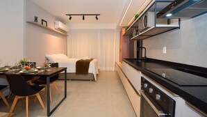 A compact hotel room with a kitchenette, a dining area, and a bed. - Studio em frente a UFSC e HU - 504R (Florianópolis)