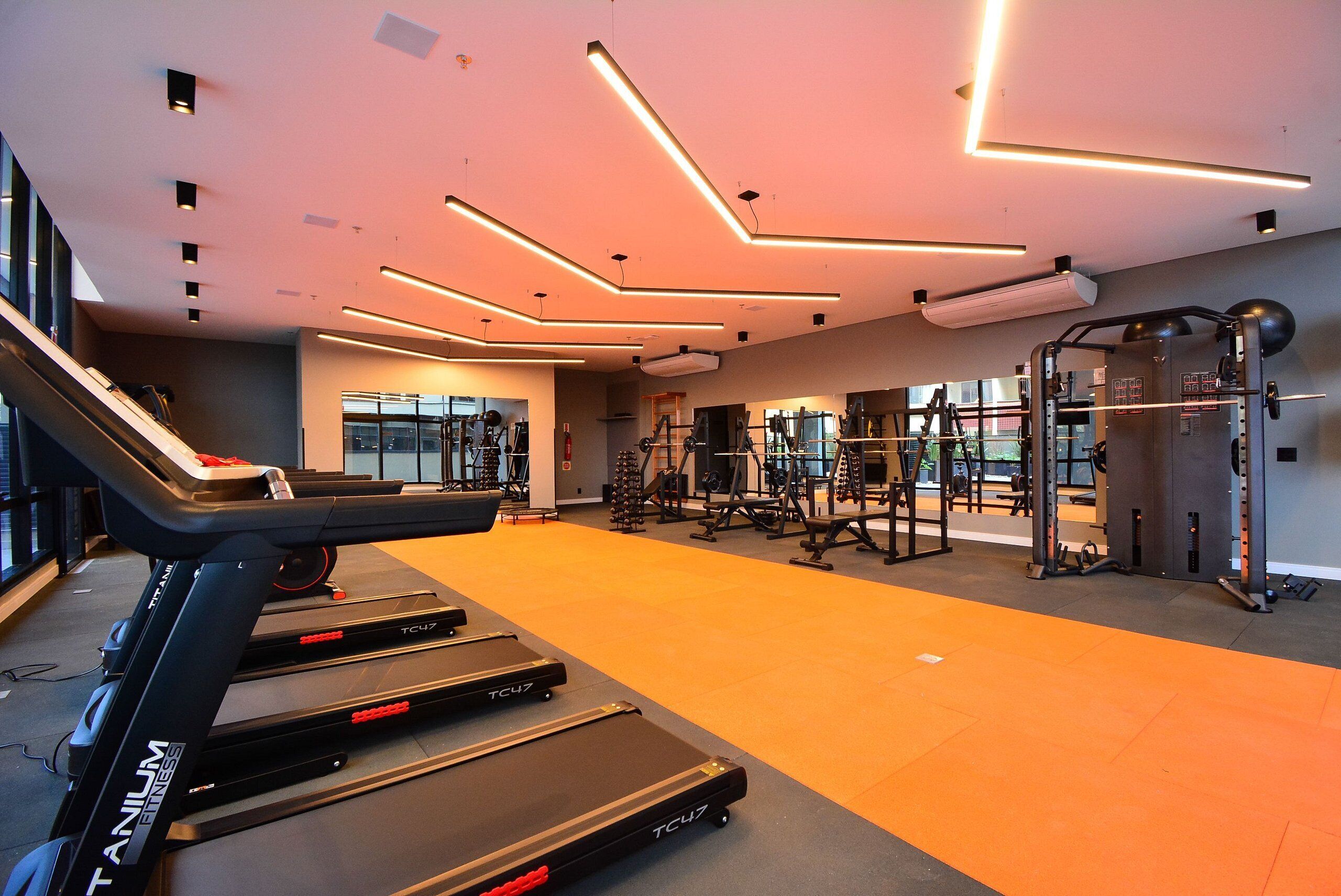 A modern gym with treadmills, weight machines, and a large mirror.