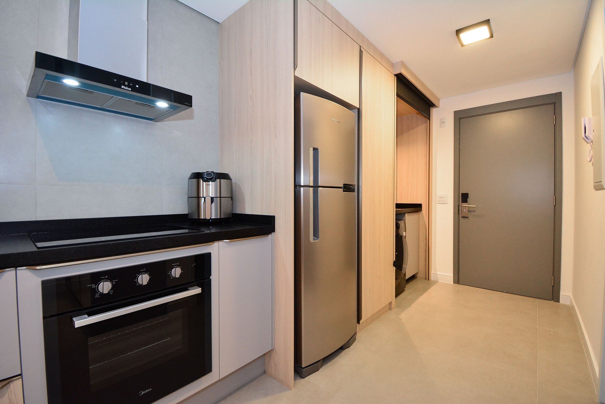Una cocina moderna con horno integrado, cafetera y refrigerador.