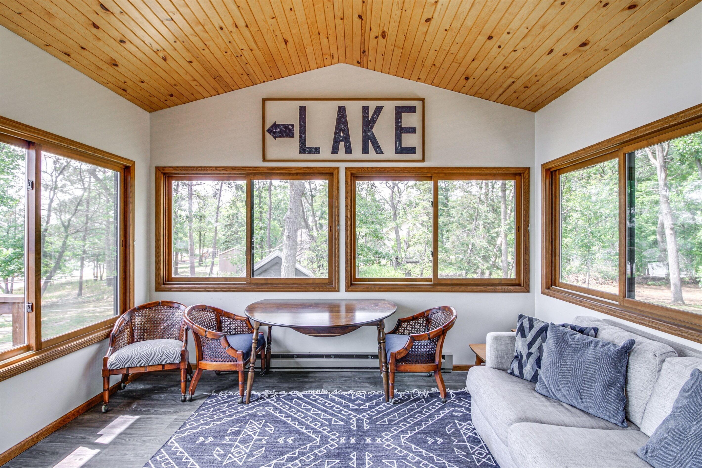 Une pièce avec vue sur le lac, un plafond en bois, une table avec des chaises et un canapé.
