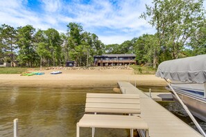 A lakeside property with a dock, boats, and a house with a deck overlooking the water.