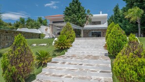 A stone staircase leading to a modern house with a covered patio and a stone wall. - Holiday Home 'Mykonos' with Sea View, Wi-Fi and Air Conditioning (Άγιοι Θεόδωροι)