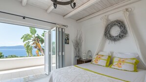 Une chambre avec un lit, une vue sur la mer, un balcon et une guirlande décorative au mur.