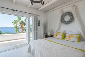 Ein Schlafzimmer mit Bett, Meerblick, Balkon und einem Kranz an der Wand.