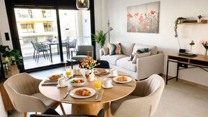 A modern living room with a dining area, a sofa, a coffee table, and a view of the outside. - Casa Anna - Velapi II - Los Alcázares (San Javier)
