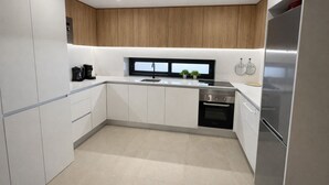 A modern kitchen with white cabinets, a stainless steel refrigerator, and a built-in oven. - Casa Anna - Velapi II - Los Alcázares (San Javier)