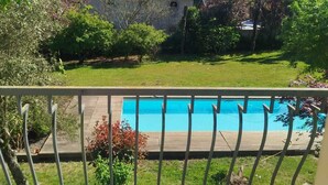 Ein Wohnhaus mit Swimmingpool, umzäunter Garten und Dachziegeldach.