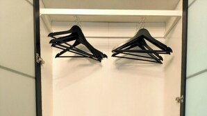 A wardrobe with two shelves, each containing a pair of black hangers and two grey storage boxes. - Top location! Modern 2-room apartment (Aschaffenburg)