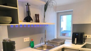 A modern kitchen with a marble countertop, stainless steel appliances, and a window providing natural light. - Top location! Modern 2-room apartment (Aschaffenburg)