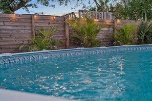 Una piscina con cerramiento de madera y plantas tropicales.