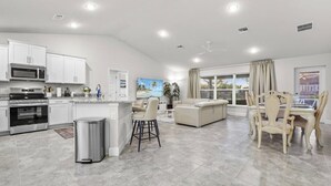 A modern kitchen with built-in appliances, a dining area with a table and chairs, and a living area with a sofa.